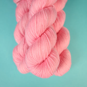 A light pink colored Sparkle yarn on top of a light blue background.