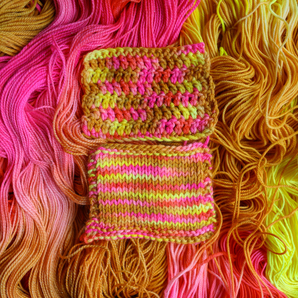 Crochet and knit swatches colored a bright yellow, pink, and a salmon pink orange, also a yellow beige color. These swatches are on top of unwound skeins of this colorway.