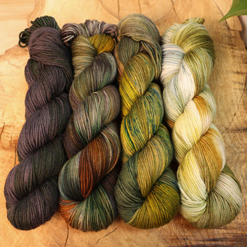 Verdant yarn set on a wooden table, that are fading from dark to light green.