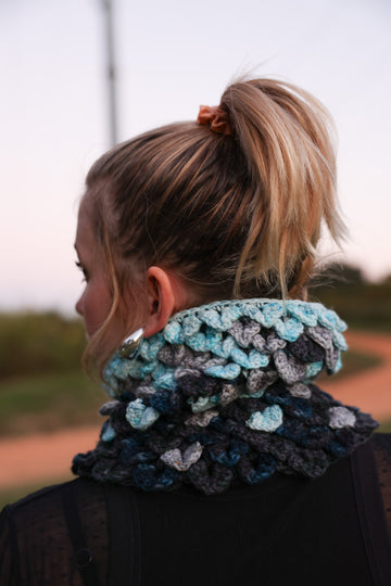 Photo of women from the back wearing Voidebane cowl, dragon scale crochet with icy blue, grey, dark blue and black colors.