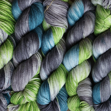 Wound skeins stacked next to each other that are Light lime green, Blue, and grey, colored with some white mixed in.
