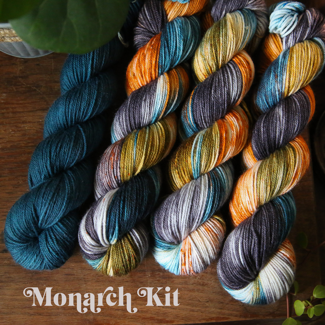 four colorful skeins of yarn arranged on a wooden surface