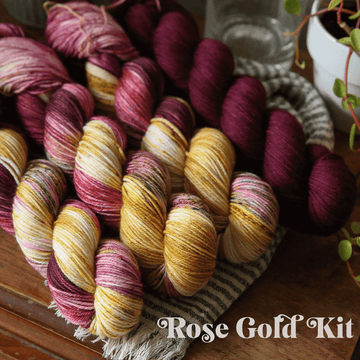 yarn skeins in rose gold and purple on a wooden surface