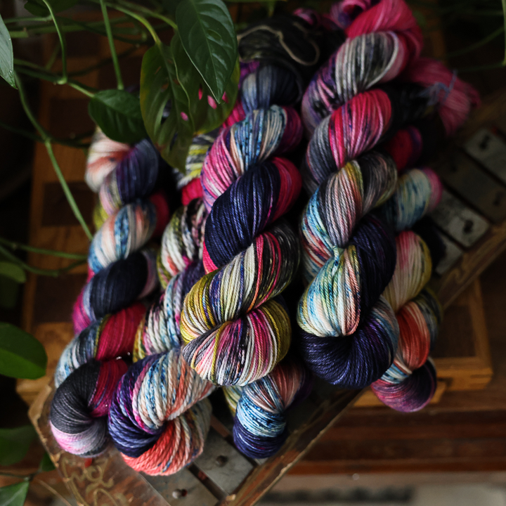 several skeins of multicolored yarn, featuring shades of pink, blue, and yellow on a wooden surface