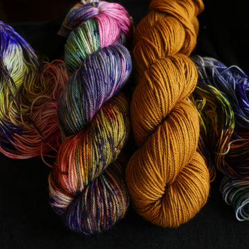Photo of Jekyll and Hyde DK set sitting on top of multicolored yarn.