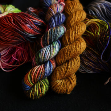 Jeykll and Hyde Dk mini set sitting on top of multicolored yarn.