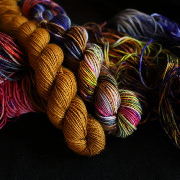 Jeykll and Hyde fingering mini set sitting on top of multicolored yarn.