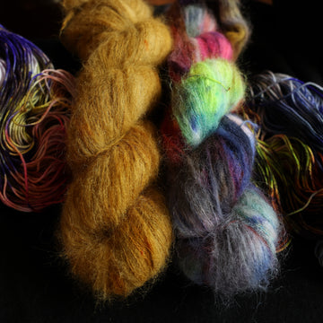 Jeykll and Hyde suri set sitting on top of multicolored yarn.