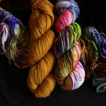 Jeykll and Hyde worsted set sitting on top of multicolored yarn.