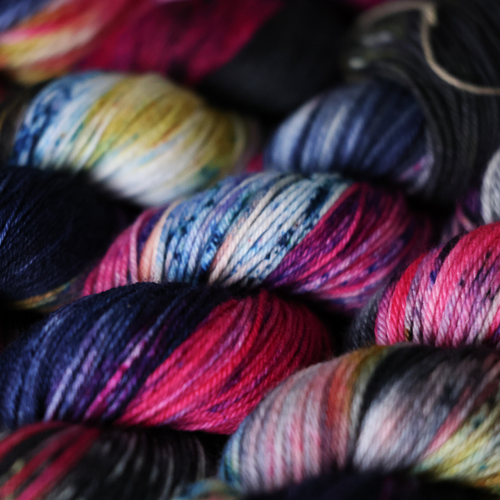 Close-up image of colorful skeins of yarn in various shades of pink, blue, and green